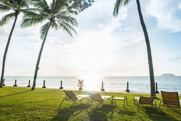 Bleiche Stühle unter der Palme mit Blick auf den Sonnenuntergang — Stockfoto