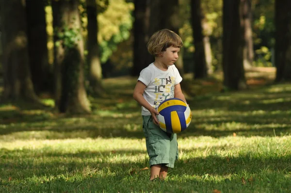 Ragazzo che gioca a calcio sull'erba. Un bambino con i capelli ricci — Foto Stock