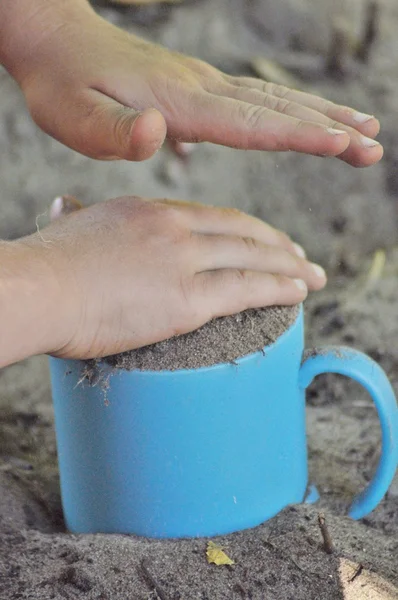 Sand, mug, child's play in the sand. Hands of the child. — Stock Photo, Image