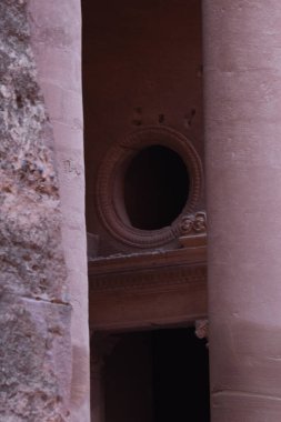 Bu büyüleyici sahne, Ürdün 'ün Petra kentindeki kayalık duvarlarla çevrili oval bir açıklığın yer aldığı antik bir taş yapıyı gösteriyor. Bölgenin tarihsel yapısını vurguluyor..