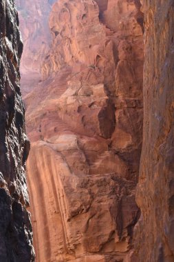 Yürüyüşçüler parlak güneş ışığı altındaki yüksek kumtaşı kayalıklarıyla çevrili dar bir kanyonu keşfediyorlar. Canlı kırmızımsı renkler, doğa aşıklarını cezbeden nefes kesici bir manzara yaratır..