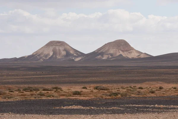 İkiz dağlar, düz çöl manzarasına hükmediyor. Pürüzsüz yamaçlarını bulutlara karşı sergiliyorlar. Arazi kuru ve kayalık, izolasyonun doğal güzelliğini vurguluyor..