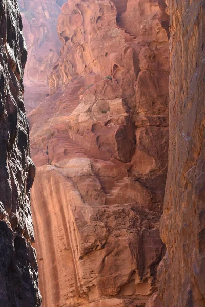 Yürüyüşçüler parlak güneş ışığı altındaki yüksek kumtaşı kayalıklarıyla çevrili dar bir kanyonu keşfediyorlar. Canlı kırmızımsı renkler, doğa aşıklarını cezbeden nefes kesici bir manzara yaratır..
