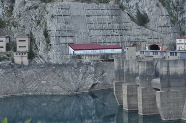 Gün batımında kayalık uçurumların ve sakin suların ardında bir baraj duruyor. Bölge uzak ve doğal güzellik ve mühendislik harikalarının bir karışımı..