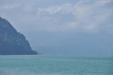 Turkuaz sular yeşil dağlar ve bulutlarla çevrili, huzur içinde uzanıyor. Sahne, doğanın sakinliğini yakalar, rahatlama ve yansıma için mükemmeldir..