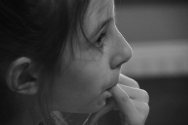 Düşüncelere dalmış genç bir kız içeride otururken parmaklarını nazikçe ısırıyor. Sahne, iç gözlem ve sakinlik anlarını yakalar. Yumuşak ışıklandırma huzurlu atmosferi güçlendirir..