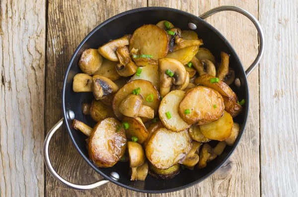 Batatas fritas com cogumelos em uma panela de ato de fritar — Fotografia de Stock