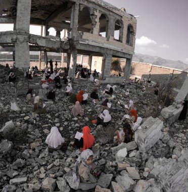 Taiz / Yemen - 23 Aralık 2018: Çocuklar Yemen 'in güneyindeki Taiz kentinde Ulusal Ordu ile Houthi milisleri arasındaki şiddetli savaş sonucu yıkılan okullarının kalıntıları üzerinde çalışıyorlar.