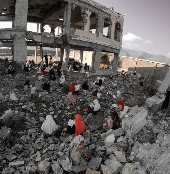 Taiz / Yemen - 23 Aralık 2018: Çocuklar Yemen 'in güneyindeki Taiz kentinde Ulusal Ordu ile Houthi milisleri arasındaki şiddetli savaş sonucu yıkılan okullarının kalıntıları üzerinde çalışıyorlar.