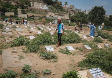 Taiz _ Yemen _ 13 Ağustos 2016: Taiz, Yemen 'deki savaş yüzünden öldürülen sivillerin mezarlarının önünde bir Yemen genci duruyor
