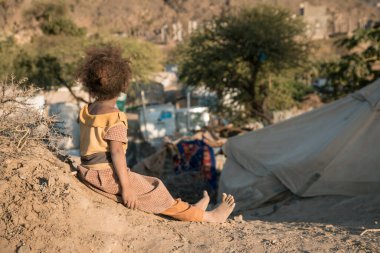 Taiz, Yemen- 04 Şubat 2021: Yemen 'deki Taiz şehrinde yerlerinden edilen insanlar için kurulan bir kampta ailesiyle birlikte yaşayan Yemenli bir kız görülüyor.