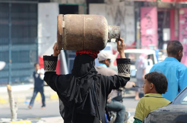 Taiz / Yemen - 17 Nisan 2020: Savaş ve Taiz, Yemen 'deki kuşatma nedeniyle başında ev gazı taşıyan Yemenli bir kadın