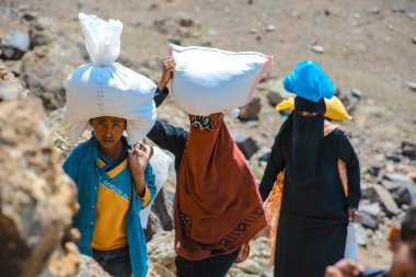 Taiz / Yemen - 2 Nisan 2017: Taiz köylerindeki Houthi milislerinin kuşatması nedeniyle Yemenli kadınlar yiyecek ve içecek ihtiyaçlarını engebeli dağ yollarından karşılıyorlar.