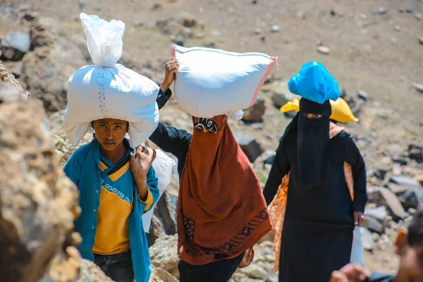 Taiz / Yemen - 2 Nisan 2017: Taiz köylerindeki Houthi milislerinin kuşatması nedeniyle Yemenli kadınlar yiyecek ve içecek ihtiyaçlarını engebeli dağ yollarından karşılıyorlar.