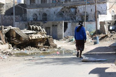 Taiz _ Yemen _ 05 Aralık 2016: Taiz, Yemen 'de savaşın yol açtığı yıkımın ortasında genç bir Yemenli yürüyor