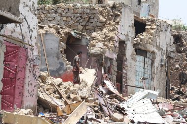 Taiz / Yemen - 17 Ağustos 2015: Yemen 'in Taiz kentindeki savaşın yıkılan statüsünün kalıntılarında bir Yemenli duruyor