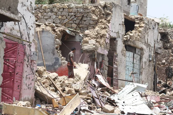 Taiz / Yemen - 17 Ağustos 2015: Yemen 'in Taiz kentindeki savaşın yıkılan statüsünün kalıntılarında bir Yemenli duruyor