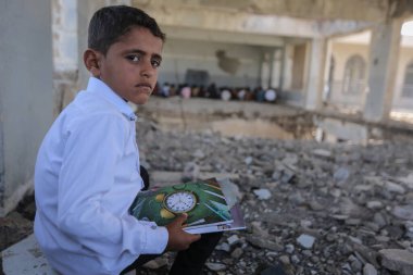 Taiz _ Yemen - 07 Oct 2020  : A sad Yemeni child sits on the rubble of his school, destroyed by the war clipart