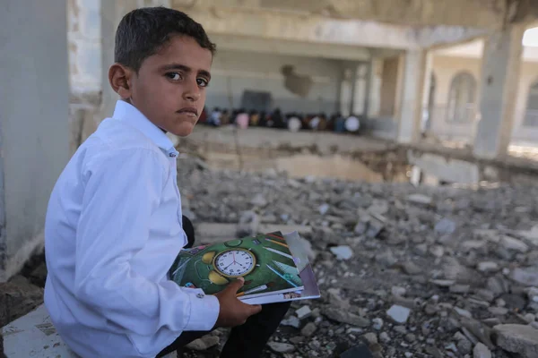 Taiz _ Yemen - 07 Ekim 2020: Üzgün bir Yemenli çocuk okulunun enkazında oturuyor, savaş tarafından yok edildi