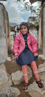 Taiz _ Yemen _ 03 Mayıs 2021: Taiz, Yemen 'deki savaş nedeniyle yıkılmış evlerin enkazında oturan bir kızın gülümsemesi