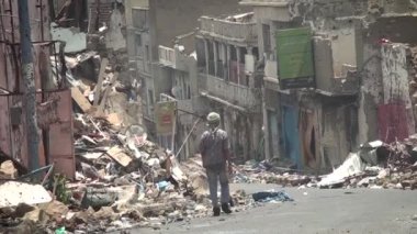 Taiz Yemen - 04 Ağustos 2015: Yemen 'in Taiz kentindeki savaş sırasında yıkılan evlerin yıkıntıları arasında Yemen' li bir adam yürüyor