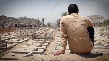 Taiz _ Yemen - 03 Nisan 2021: Bir Yemen ağızlık takıyor ve Yemen 'deki Corona salgını yüzünden ölen insanların mezarlarına hüzünlü bir şekilde bakıyor, Taiz