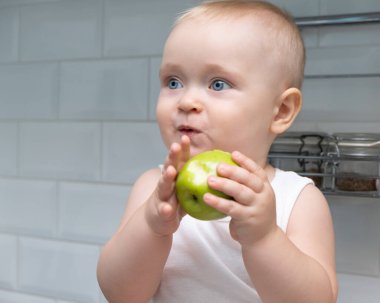 Bebek beyaz arka planda elma yiyor. bebek maması konsepti.