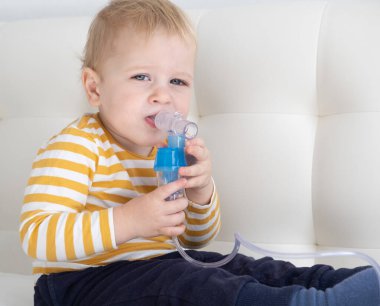 Küçük bebek yatakta buhar spreyi nebulizörü kullanıyor. kopyalama alanı. sağlık hizmetleri.