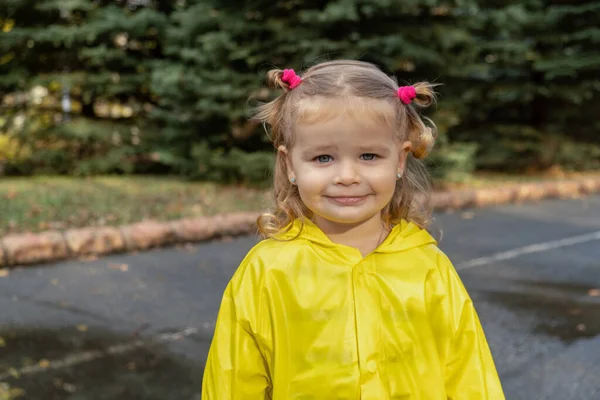 Милая блондинка малышка в желтом стильном плаще крупным плащом. детство. — стоковое фото