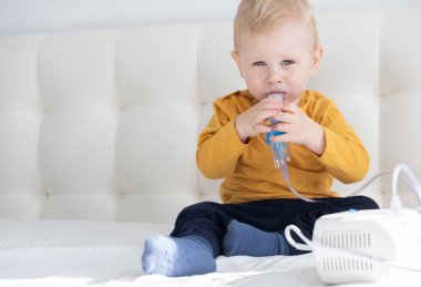 Küçük bebek kendisi de yatakta buhar spreyi nebulizörü kullanıyor. kopyalama alanı. sağlık hizmetleri.