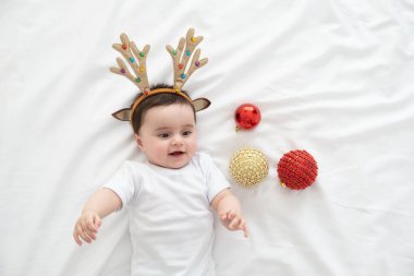 Noel süslemeleri ile beyaz yatak üzerinde uzanan küçük kız..