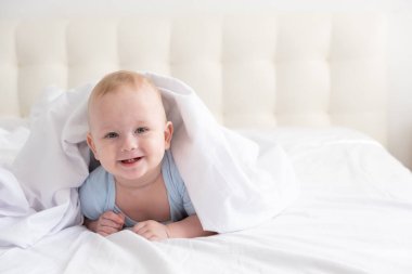 Evdeki beyaz bir yatakta gülümseyen ve yatan komik çocuk.. 