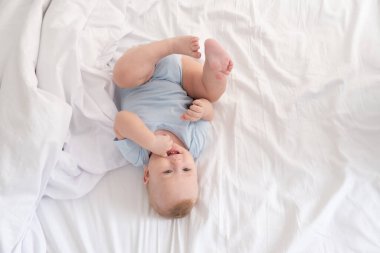 Komik çocuk beyaz yatak üzerinde evde yatıyordu. en üstteki görünüm.