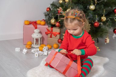 Noel ağacının yanında boynuzları geyik boynuzlu küçük kız hediyesini açıyor..
