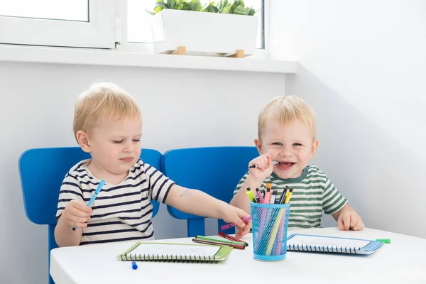 Образование и хобби. Два блондинистых близнеца мальчики рисуют войлочной ручкой. — стоковое фото