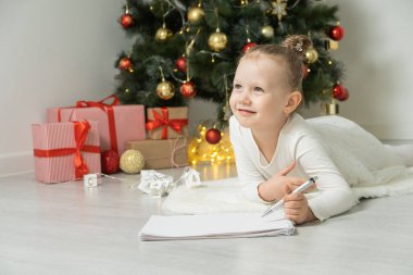 Mutlu çocuk Noel ağacının yanında Noel Baba 'ya mektup yazıyor. İyi tatiller..