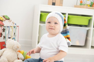Yavru bebek evde oyuncak ayı ve yemek ile oynuyor. Çocuklar için oyunlar geliştiriliyor.