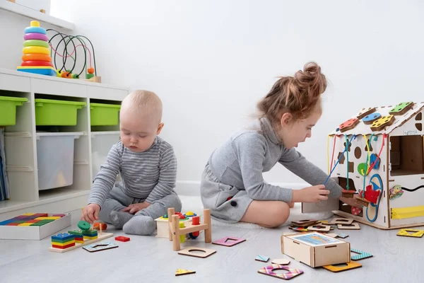 Мальчик играет со старшей сестрой с деревянными игрушками. раннее развитие детей. — стоковое фото