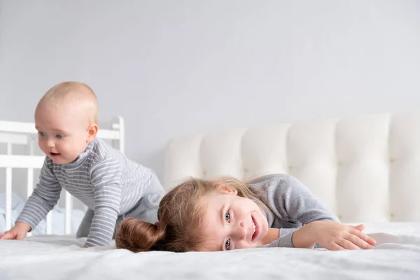 Mały chłopiec i mała siostrzyczka bawią się w domu w łóżku. Home zajęcia dla dzieci. — Zdjęcie stockowe