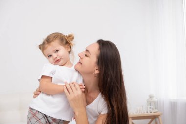 Yetişkin bir anne küçük kızını kucaklıyor, eğleniyor.