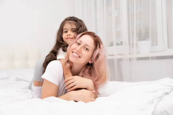 Jovem Mãe Pequena Filha Ativa Deitada Cama Casa Abraçando Divertindo — Fotografia de Stock