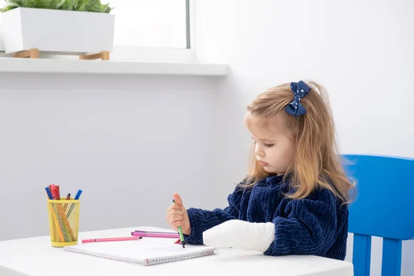 Маленькая Девочка Рукой Гипсе Сидит Столом Пытаясь Рисовать Маркерами — стоковое фото
