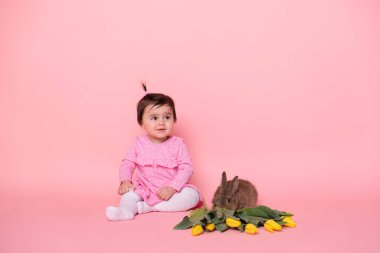 Tatlı kız tavşan ve pembe arka planda sarı laleler. bahar ve Paskalya