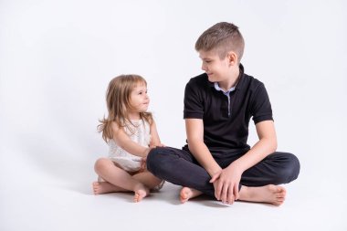 Yakışıklı abi genç kız kardeşiyle birlikte beyaz arka planda oturuyor..