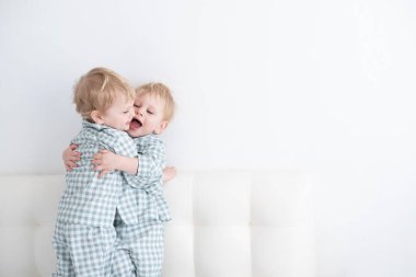 Beyaz arka planda pijamalarıyla sarılan iki bebek ikiz çocuk.