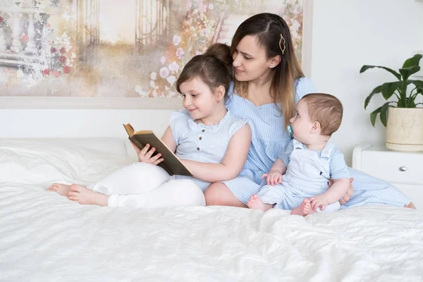 Anne, iki çocuklu bir kitap okuyor. Oğlu ve küçük kızı yatakta.