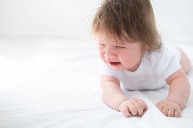 sağlıklı erkek bebek ağlar ve beyaz bir yatakta yatar.