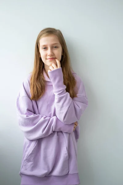 Dospívající Dívka Dlouhými Vlasy Fialové Huddy Stojící Proti Bílé Zdi — Stock fotografie