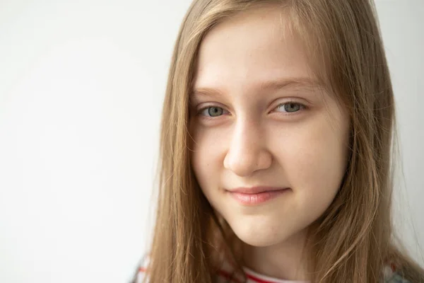 Portrait of beautiful teenage girl with long hair smiling standing against white wall — Stock Photo, Image