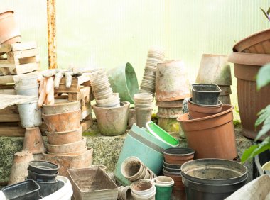 Toprakla kaplı bitkiler için çeşitli kullanılmış plastik ve kil kaplar..